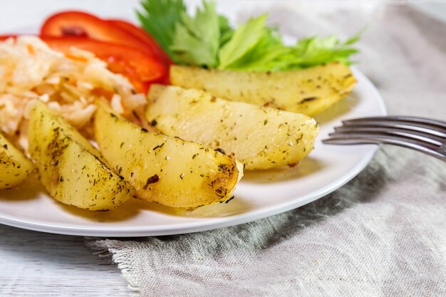 Fried potatoes with sauerkraut, sweet peppers and celery in a white plate.