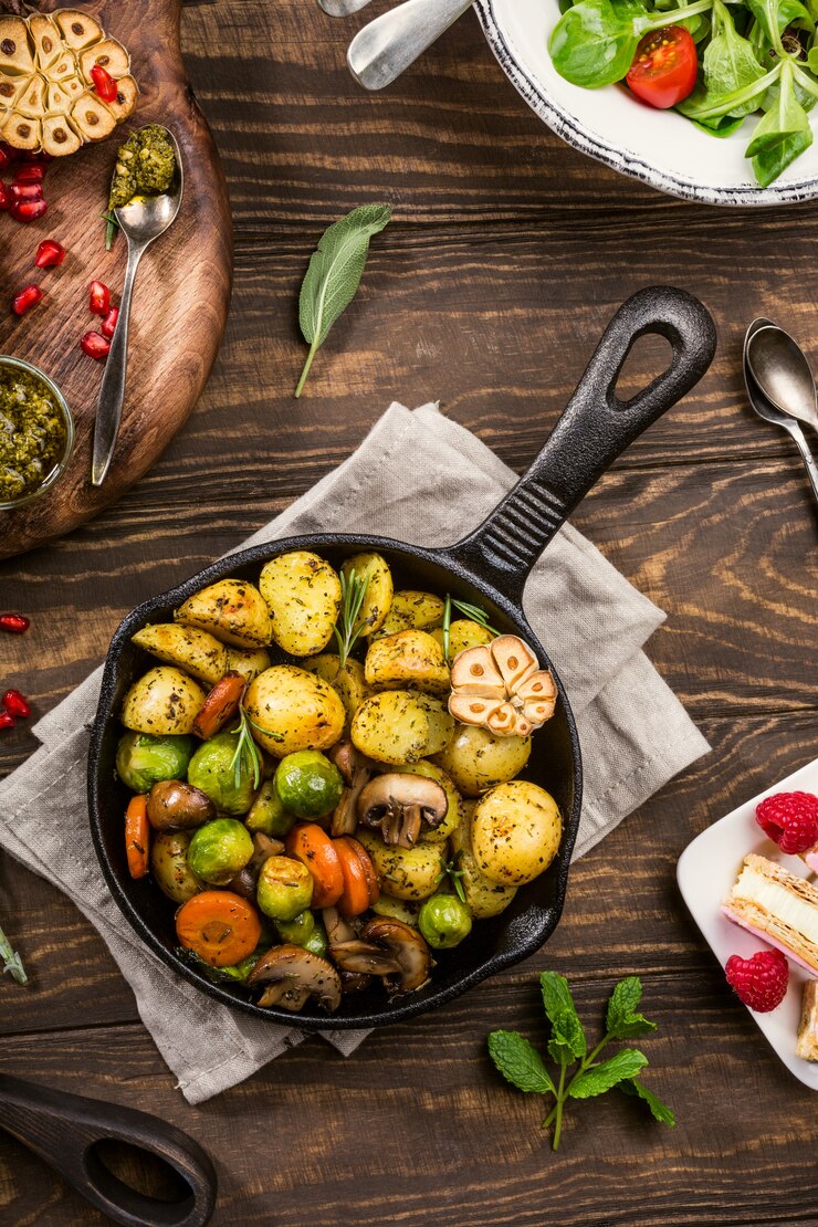 Жареный картофель с овощами и зеленью на деревянных фоне.