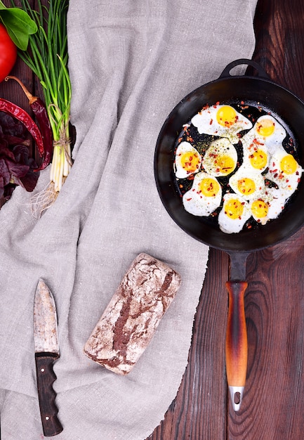 Fried quail eggs in a cast-iron black frying pan 