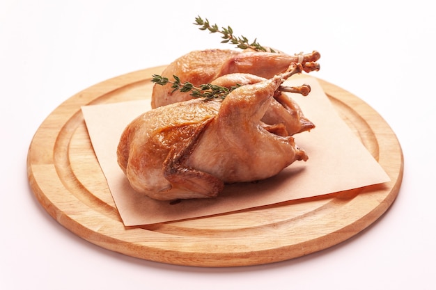 Fried quail on a wooden cutting board isolated on a white