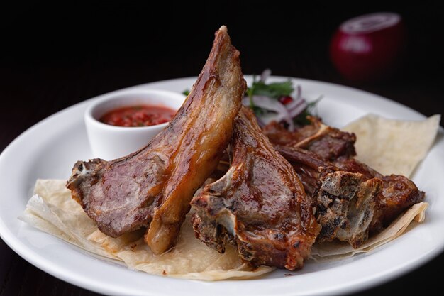 Fried ribs su un piatto bianco con salsa e cipolle