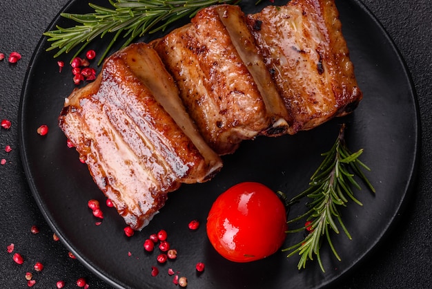 Fried ribs with rosemary, onion, sauce. Dark table.