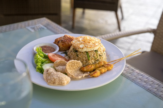 Fried rice served with fried chicken fried egg and satay