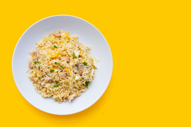 Fried rice in white plate on yellow background.