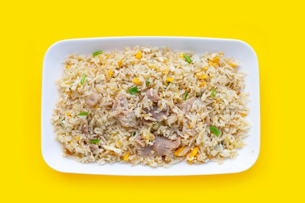 Fried rice in white plate on yellow background.