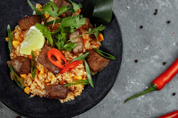 Photo fried rice with beef and vegetables on a gray textured background