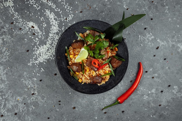 Fried rice with beef and vegetables on a gray textured table.