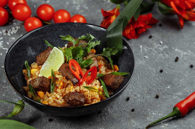 Fried rice with beef and vegetables on a gray textured.