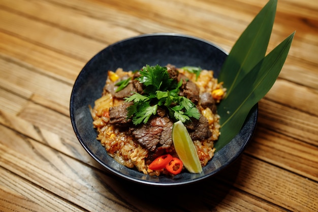 Photo fried rice with beef and vegetables on wooden background