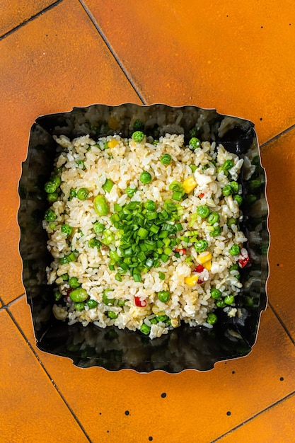 Fried rice with egg and vegetables in box take away Orange background Top view