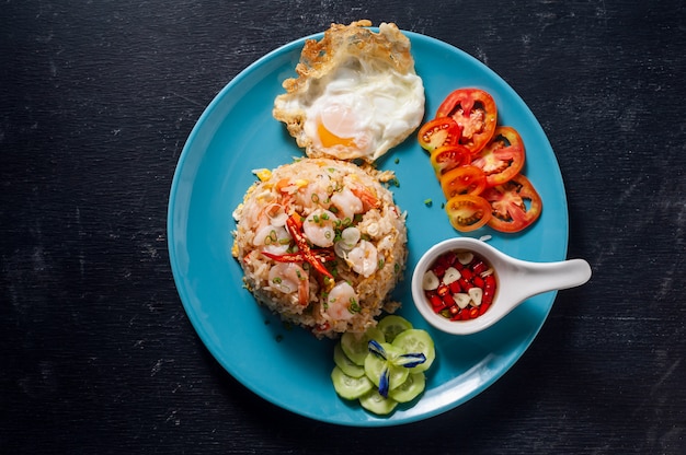 Photo fried rice with shrimp and fried egg on black wooden table, thai food.