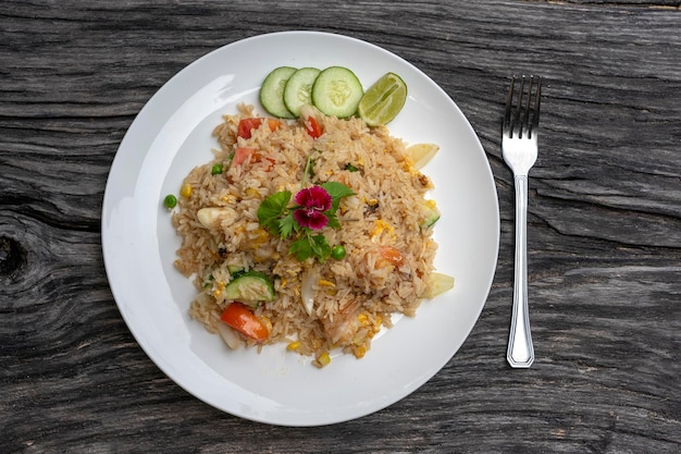 Fried rice with shrimps and vegetables in a white dish on an old wooden table close up Thai food Thai cuisine