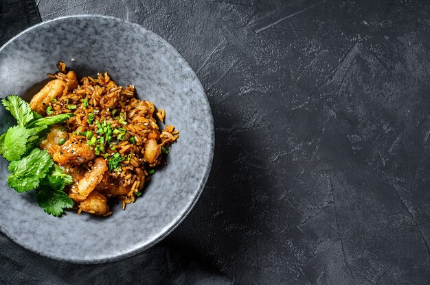 Fried rice with spicy sauce and shrimps, prawns. Black background