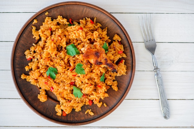Жареный рис с овощами и курицей в соусе в тарелке на белом столе