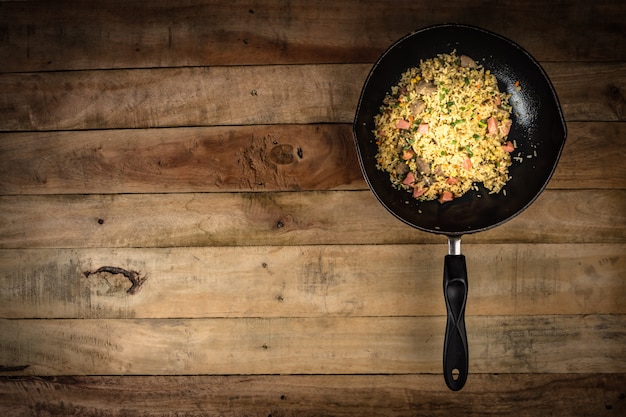 жареный рис с овощами, мясом и яичницей подается на тарелке с палочкой