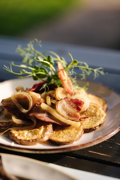 Fried ring potatoes with bacon in a plate outdoor summer terrace