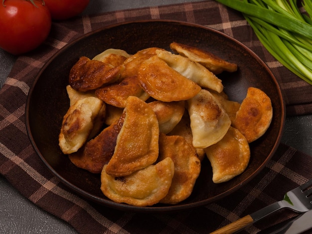 Fried Russian dumplings decorated with tomatoes and green onions