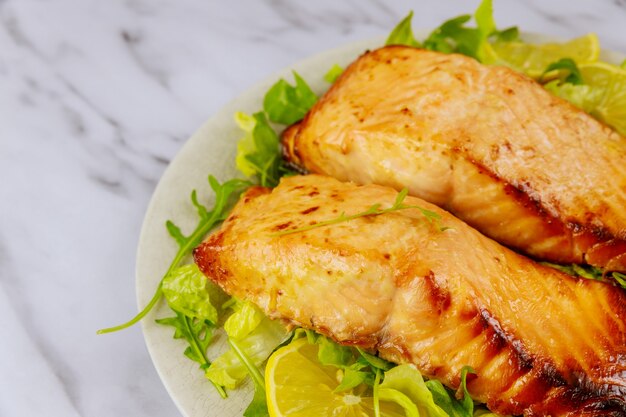 Fried salmon fillet with green salad on white plate. Healthy food.