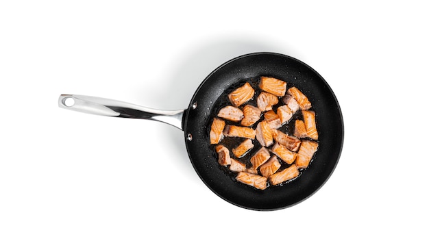 Fried salmon slices in a frying pan isolated.