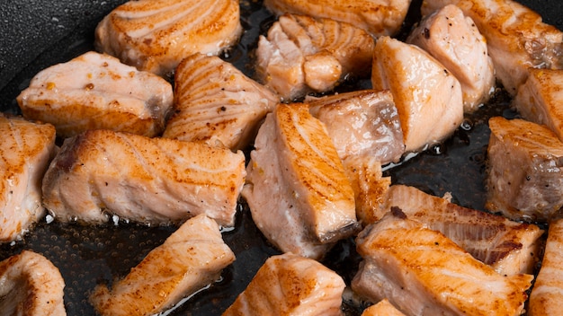 Fried salmon slices in a frying pan isolated.