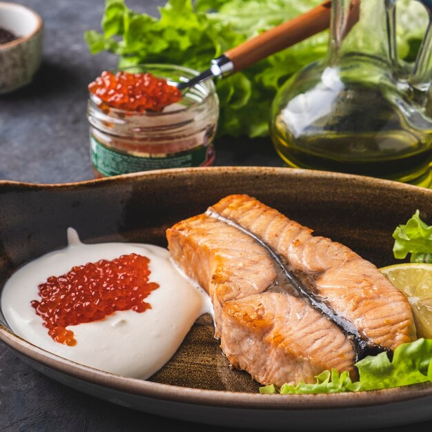 Fried salmon steak with cream and caviar on a plate