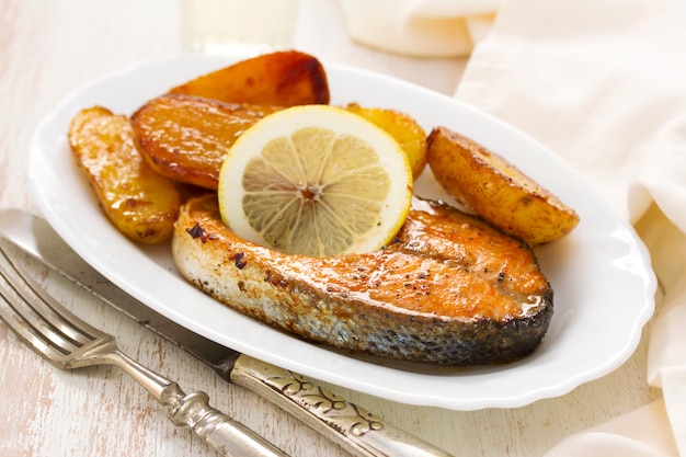 Fried salmon on white plate on wooden surface