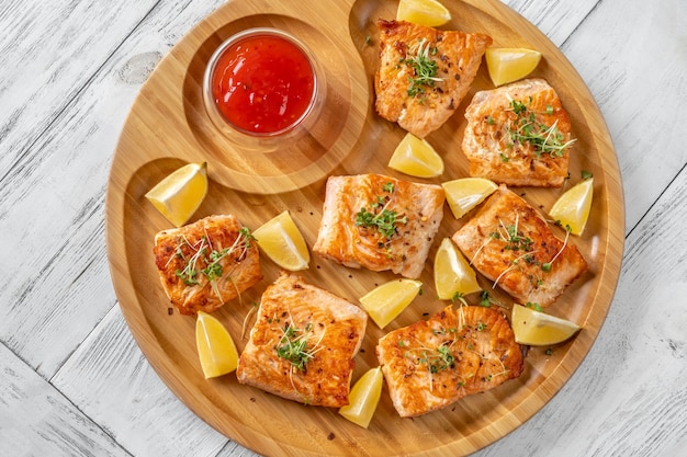 Fried salmon with sauce on the wooden serving tray