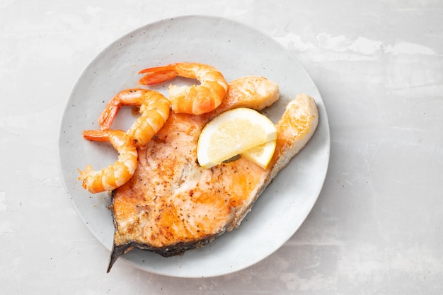 Salmone fritto con gamberetti sul piatto bianco