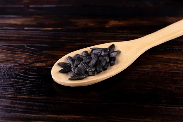 Fried salted sunflower seeds in a wooden spoon  on a dark wooden background