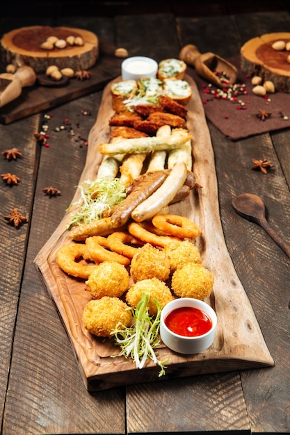 fried salty beer snacks on the wooden board with sauces