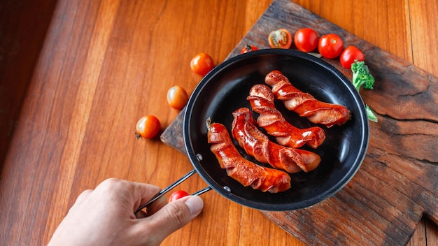Fried sausage in a black pan in the chef hands