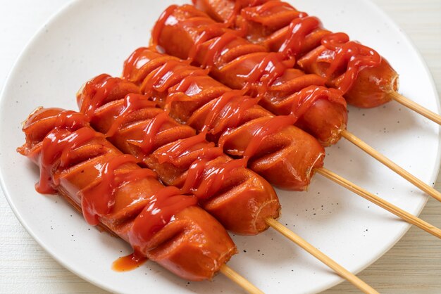 fried sausage skewer with ketchup on white plate