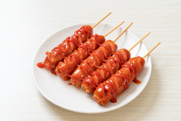 fried sausage skewer with ketchup on white plate