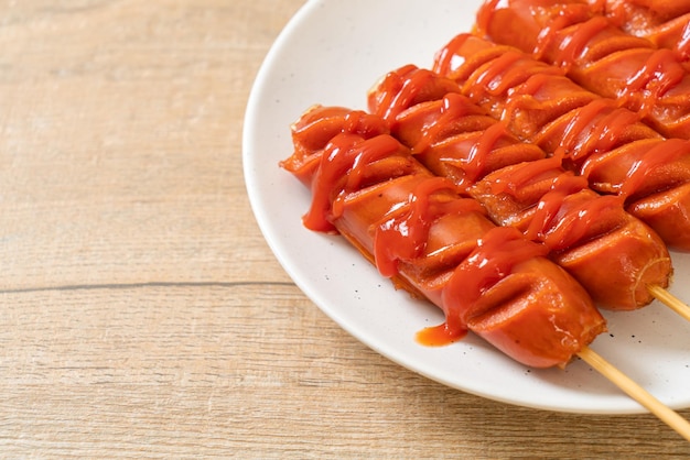 fried sausage skewer with ketchup on white plate