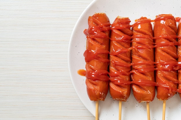 Fried sausage skewer with ketchup on white plate