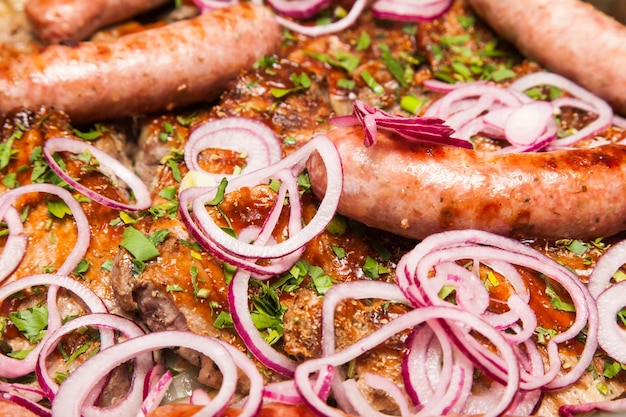 Fried sausages and meat sprinkled with fresh chopped onions and herbs