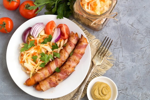 Fried sausages with bacon on a plate.