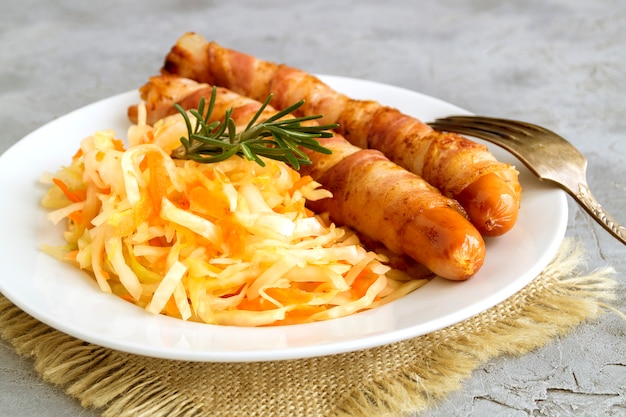 Fried sausages with bacon on a plate.