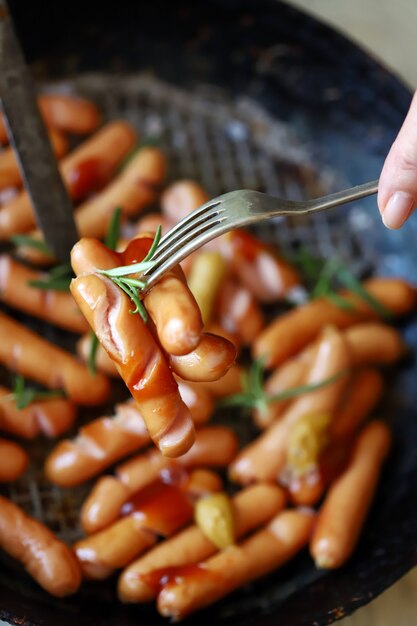 Photo fried sausages with a crispy crust. beer snack. german spiced sausages in a frying pan.