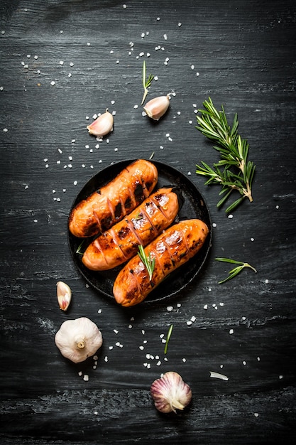 Fried sausages with garlic and herbs in a pan