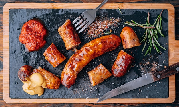 Fried sausages with sauces and spices on a stone plate