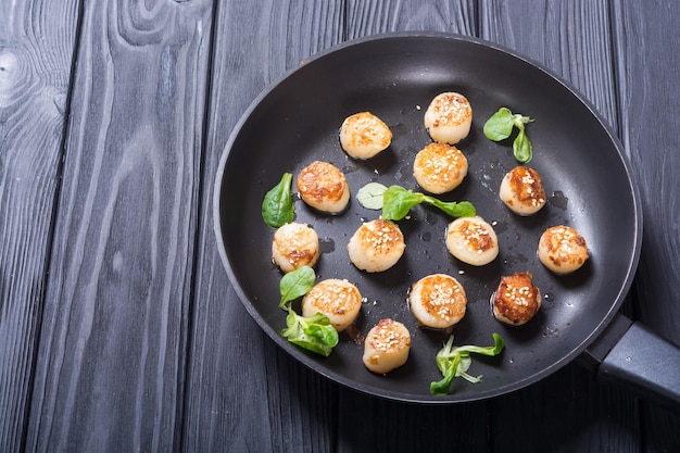 Fried scallops with lemon and salad Seafood background