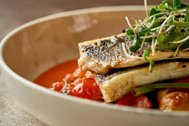 Filetto di branzino fritto con patate in salsa di pomodoro primo piano di messa a fuoco selettiva