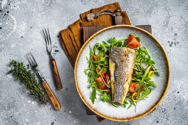 Fried sea bass fillet with vegetable salad Dicentrarchus fish Gray background Top view