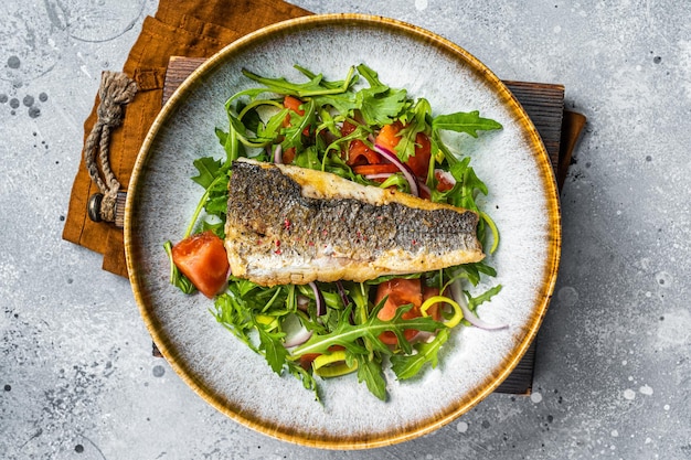 Fried sea bass fillet with vegetable salad Dicentrarchus fish Gray background Top view