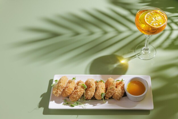 Fried shrimp with a cocktail on a light green background with a shadow from a palm tree top view