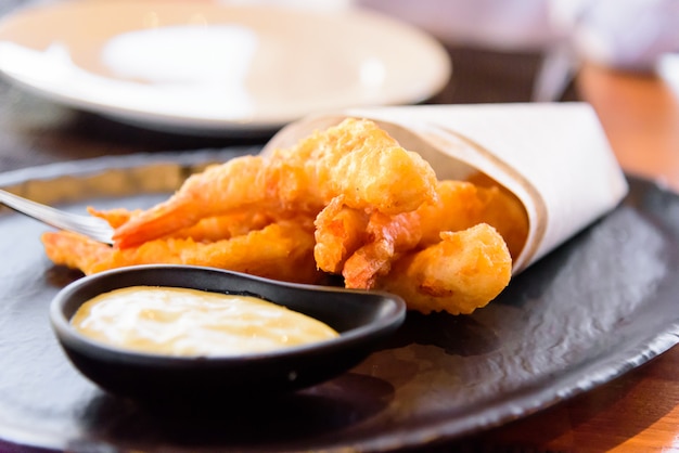 Photo fried shrimp with mayonnaise on black plate.