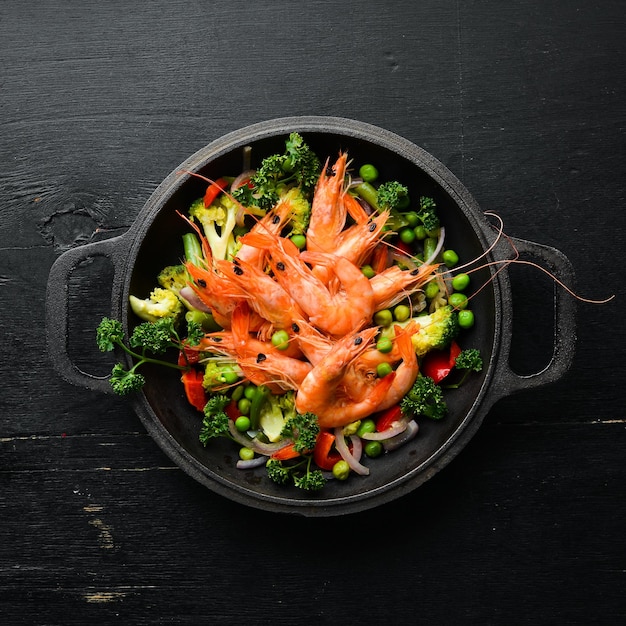 Fried shrimp with vegetables in a frying pan Seafood Top view Free space for your text