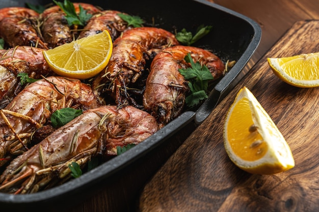 Fried shrimps on grill pan with fresh herbs and lemon slice.