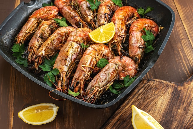 Fried shrimps on grill pan with fresh herbs and lemon slice.